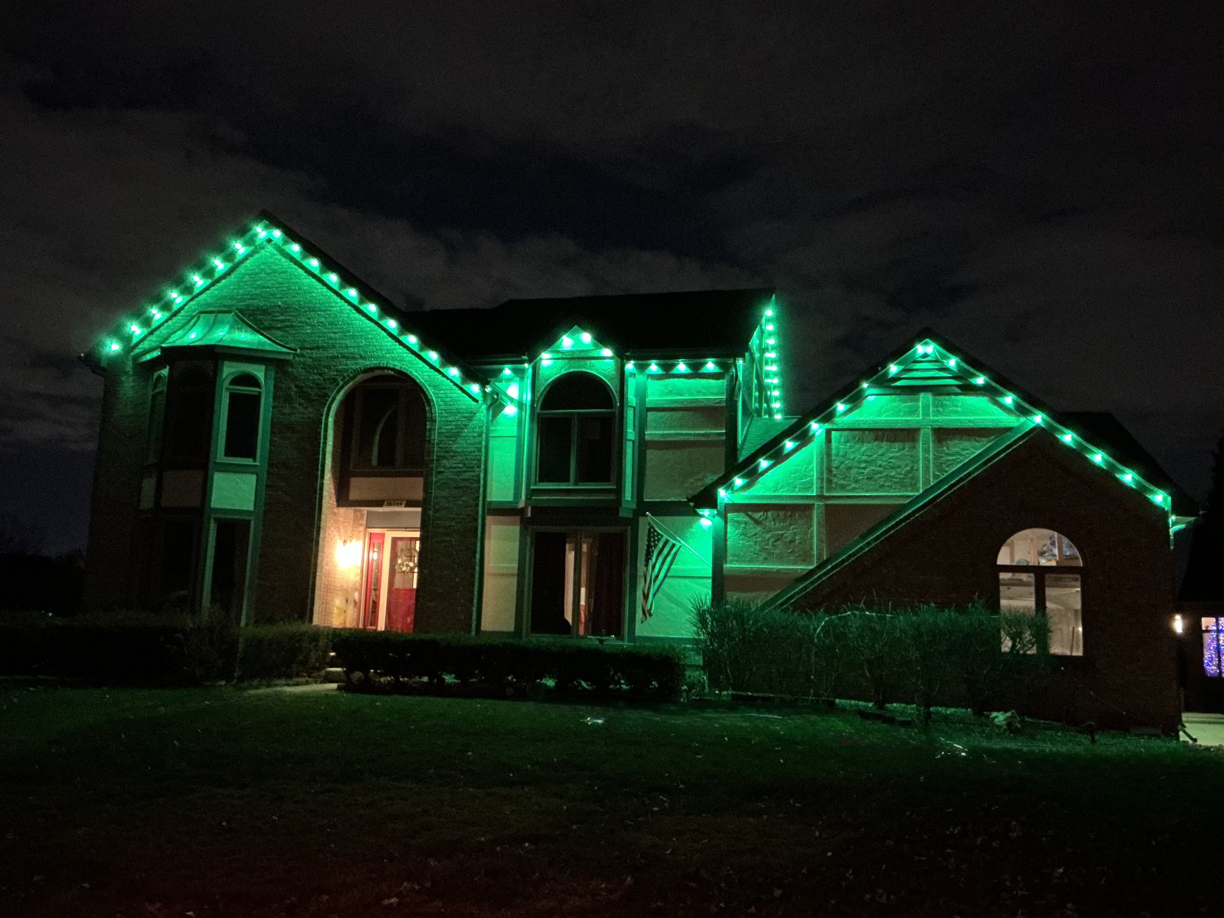 Green holiday roofline lighting installation on a home