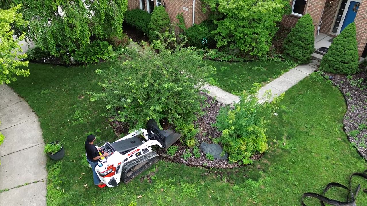 SB Outdoor Solutions crew operating a mini skid steer on a landscape project